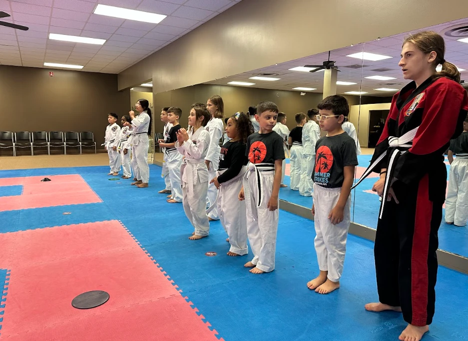 Female karate instructor guiding a line of young students at Murray's Martial Arts dojo.