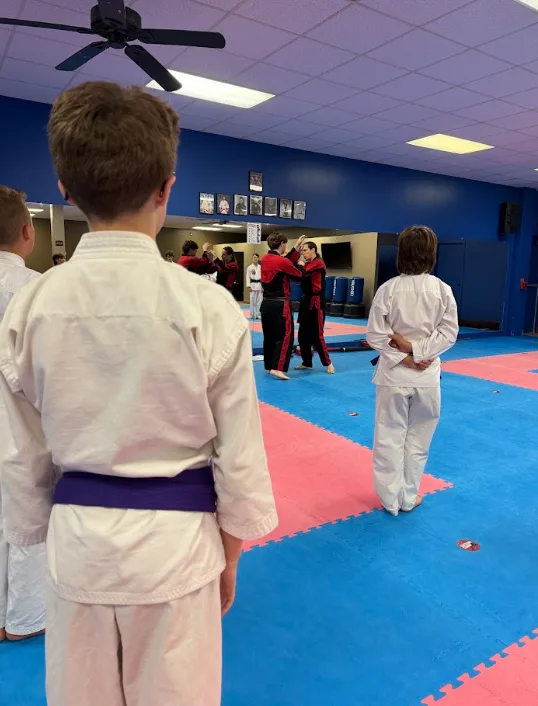 Young karate student observing structured class drills on safe mats in Greece, NY.