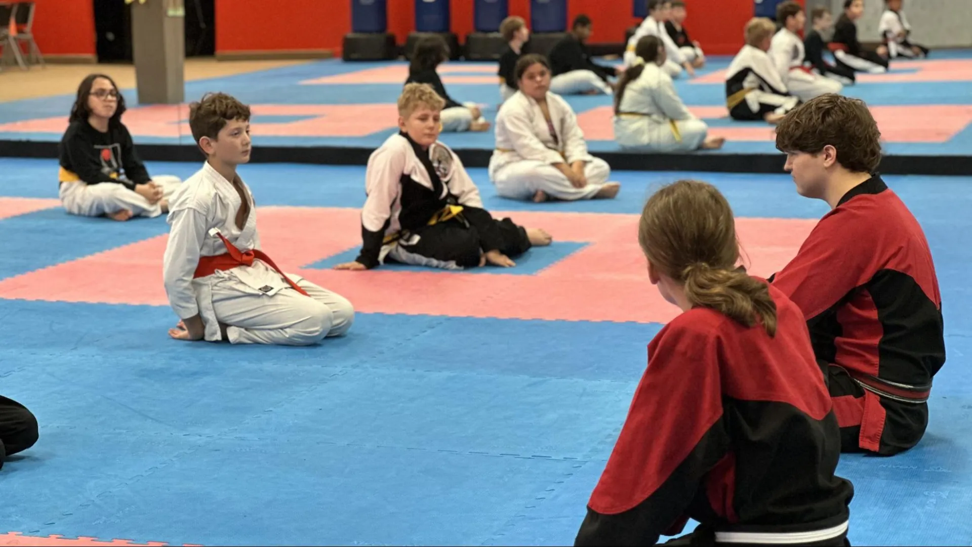 Young karate students sitting attentively while instructors lead class at Murray's Martial Arts