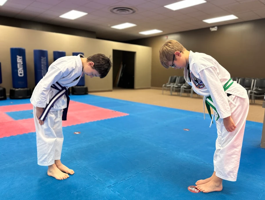 Two youth karate students bowing with respect before partner drills in Greece, NY.