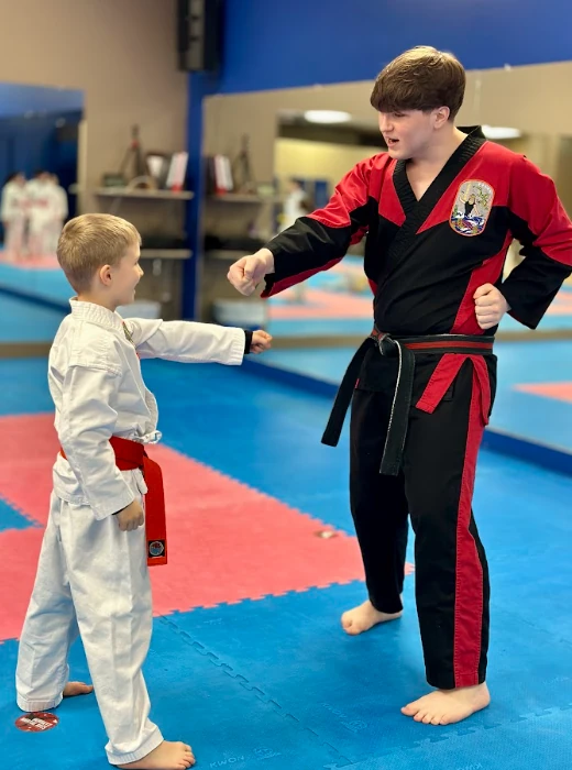 Karate instructor guiding a young student through punch mechanics in Greece, NY.