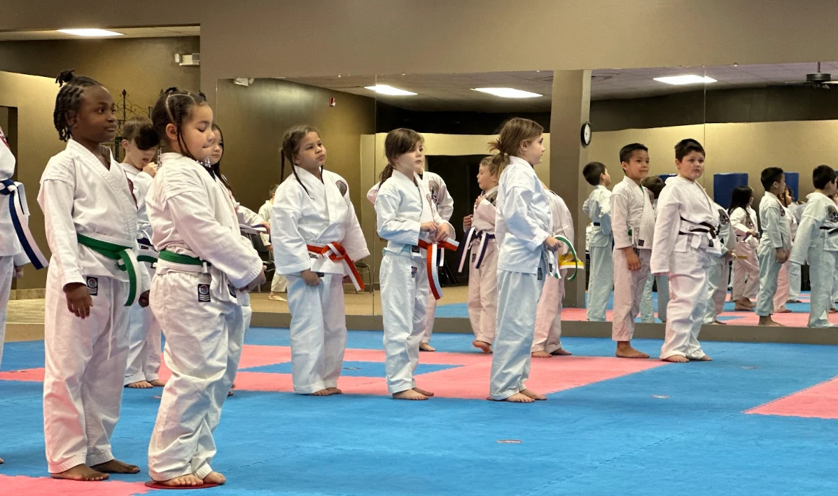 Children standing in a disciplined row during kids karate class in Greece, NY.