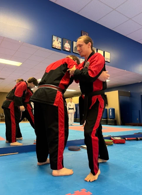 Karate instructor coaching a young student on proper technique at Greece NY dojo.