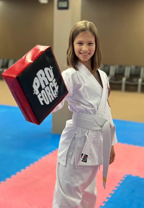 Young girl in karate uniform holding a target pad at Murray's Martial Arts in Greece, NY.