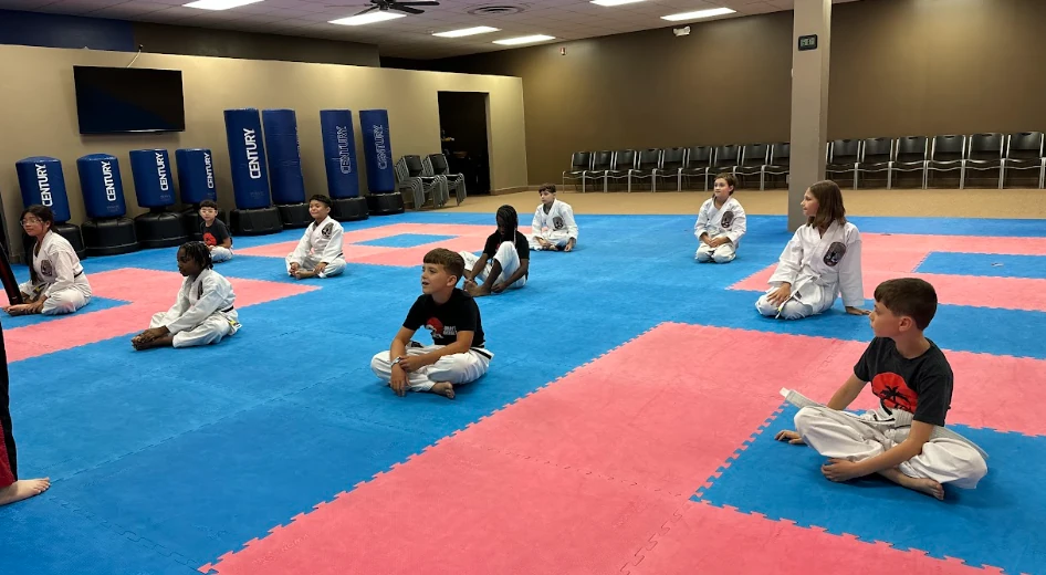 Children sitting attentively on the mats during karate class in Greece, NY.