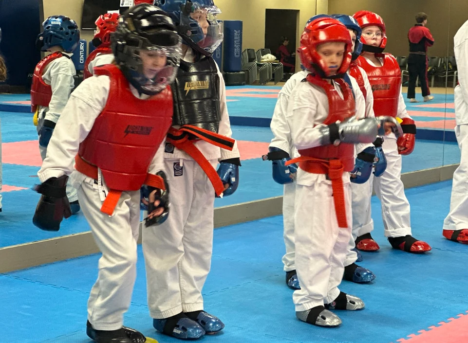 Young students in protective martial arts gear ready for class at Greece NY dojo.