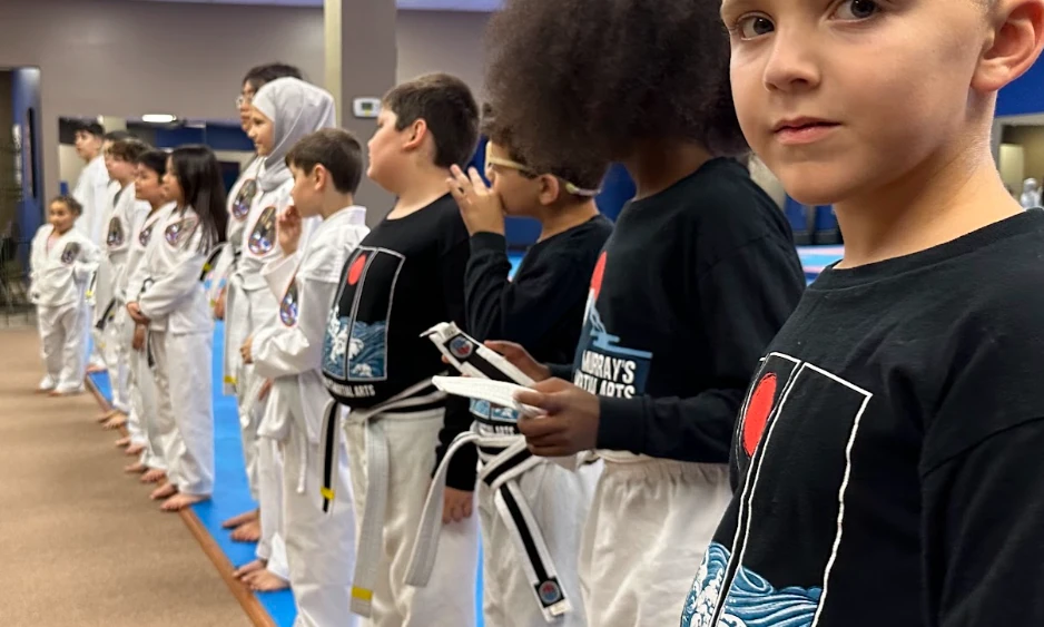 Young students standing in line learning listening skills at Murray's Martial Arts dojo.