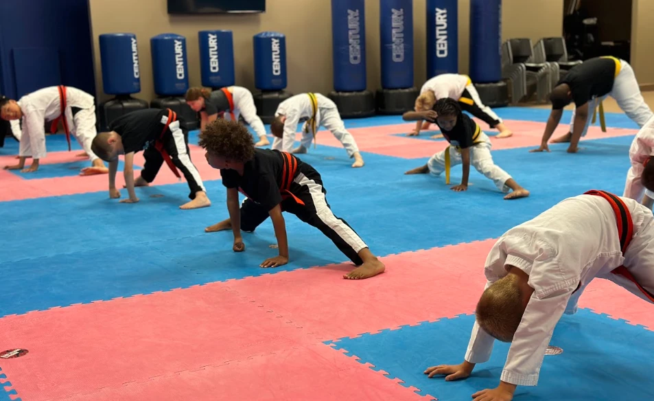 Kids stretching and warming up on safe mats during youth karate class in Greece, NY.