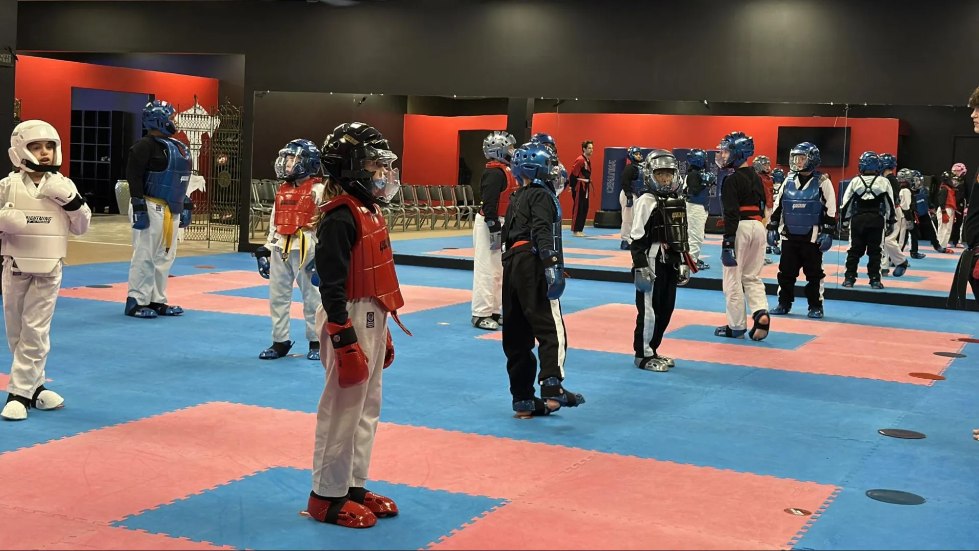 Kids in protective sparring gear lining up on the mat at Murray's Martial Arts in Greece, NY